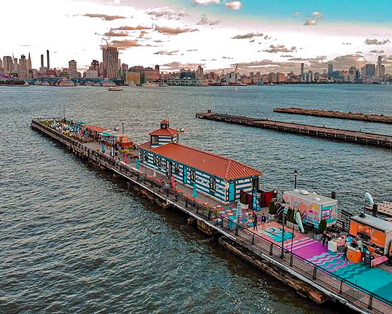 Aerial view of Pier 13 Hoboken stretching into the water with the Manhattan skyline behind